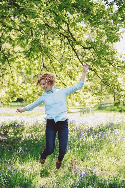 Eine glückliche junge Frau springt über ein Grasfeld