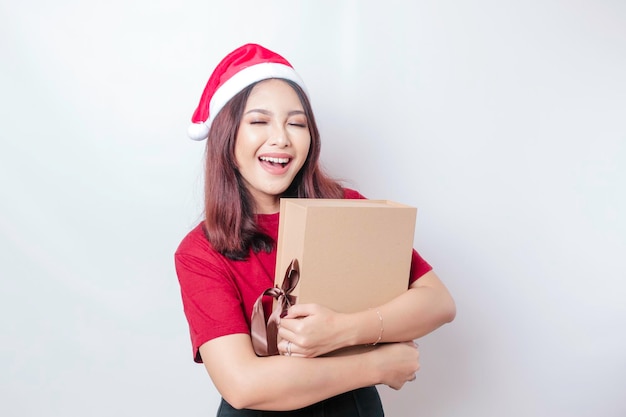 Eine glückliche junge Frau trägt Santa Claus39-Hut und hält Weihnachtsgeschenke