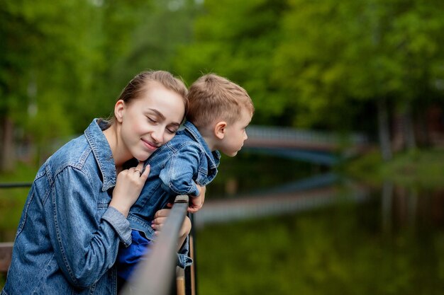 Eine glückliche junge Mutter spielt und amüsiert sich mit ihrem kleinen Sohn an einem warmen Frühlings- oder Sommertag im Park.