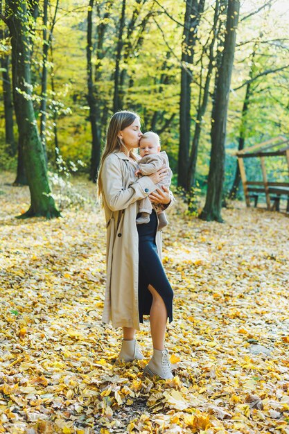 Foto eine glückliche junge mutter umarmt ihren kleinen sohn in der sonne an einem warmen frühlings- oder sommertag im park die sonne scheint hell in einem apfelgarten oder in einem park mutter und sohn familienkonzept in der natur