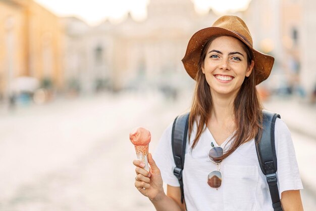 Foto eine glückliche junge touristin isst eis in rom, italien. eine junge frau mit einem sommerhut.