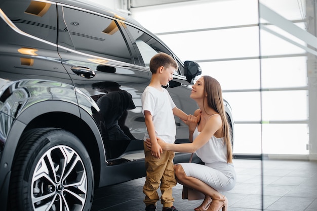 Eine glückliche Mutter mit ihrem kleinen Sohn wählt ein neues Auto bei einem Autohaus