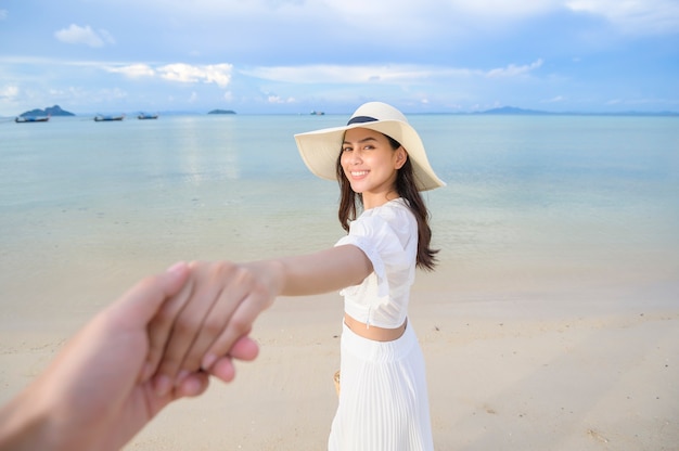Eine glückliche schöne Frau im weißen Kleid, die am Strand-, Sommer- und Feiertagskonzept genießt und sich entspannt