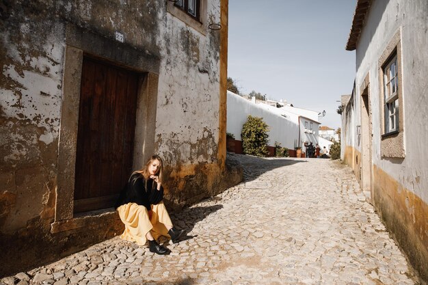 Eine glückliche Touristenfrau mit schwarzem Hut überblickt die bunte Altstadt in Portugal