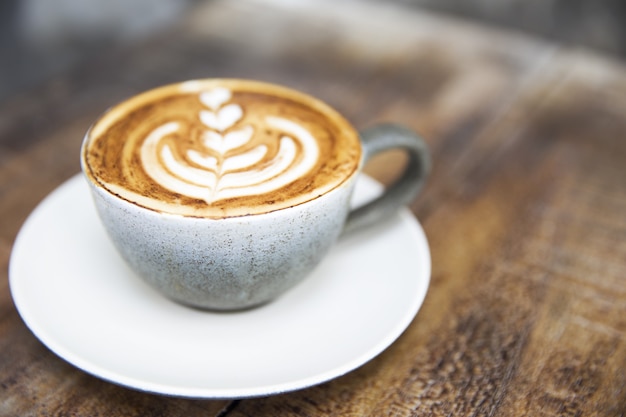 Eine graue Keramiktasse Cappuccino mit schöner Latte Art auf holzbraunem Hintergrund