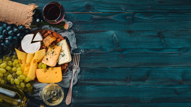 Eine große Auswahl an Käse, Wein, Honig, Nüssen und Gewürzen auf einem blauen Holztisch Draufsicht Freier Platz für Text