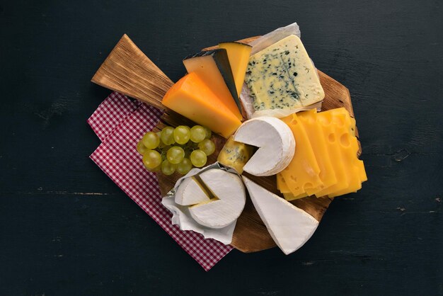 Eine große Auswahl an Käsesorten Mozzarella Blauschimmelkäse Brie Käse Maasdam Draufsicht auf schwarzem Hintergrund aus Holz Freier Platz für Ihren Text