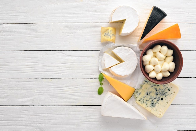 Eine große Auswahl an Käsesorten Mozzarella Blauschimmelkäse Brie Käse Maasdam Draufsicht auf weißem Hintergrund aus Holz Freier Platz für Ihren Text