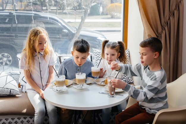 Eine große, freundliche Gesellschaft von Kindern feiert den Urlaub in einem Café mit einem köstlichen Dessert. Der Tag der Geburt.