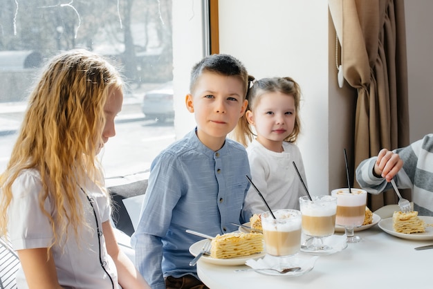 Eine große, freundliche Gesellschaft von Kindern feiert den Urlaub in einem Café mit einem köstlichen Dessert. Der Tag der Geburt.