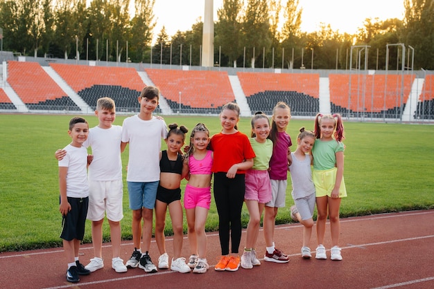 Eine große Gruppe von Jungen und Mädchen freut sich gemeinsam und winkt während des Sonnenuntergangs nach dem Spiel mit den Händen im Stadion Ein gesunder Lebensstil