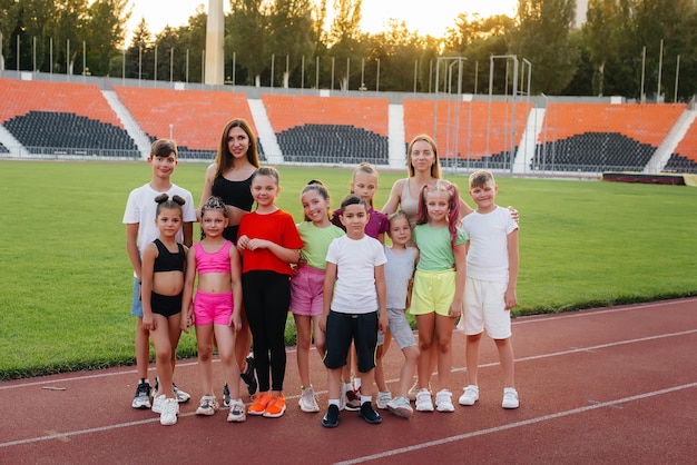 Eine große Gruppe von Jungen und Mädchen freut sich gemeinsam und winkt während des Sonnenuntergangs nach dem Spiel mit den Händen im Stadion Ein gesunder Lebensstil