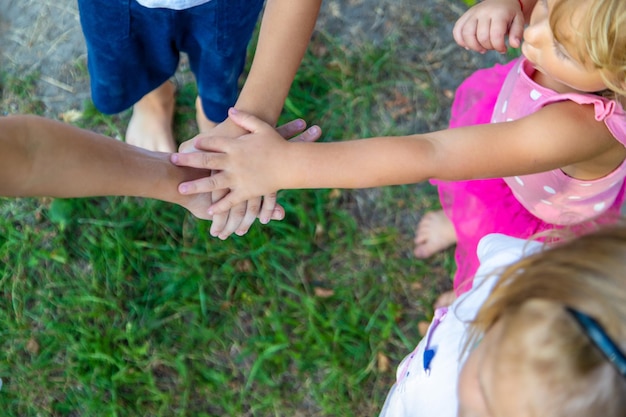 Foto eine große gruppe von kindern, jungen und mädchen, stehen zusammen in einem kreis und legen ihre hände zusammen, stellen sich auf und erheben den teamgeist vor dem spiel