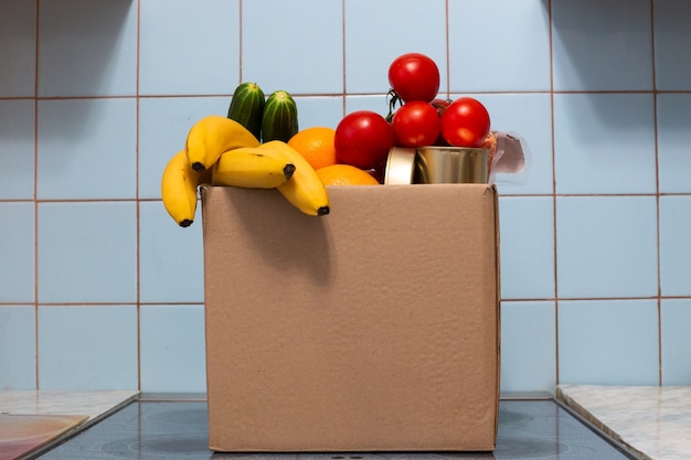 Eine große Kiste mit Essen und Gemüse steht in der Küche, Spenden für Bedürftige während der Selbstisolation und Quarantäne