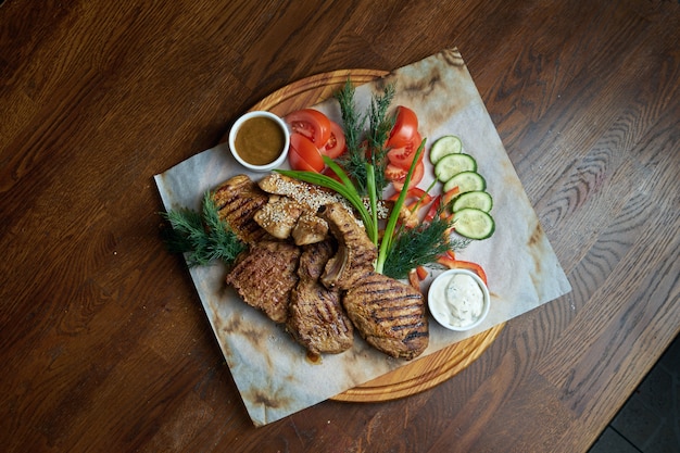 Eine große Portion gegrillten Kebab. Schweinefilet, Steak am Knochen, gekocht in einem Grill mit verschiedenen Saucen und frischem Gemüse. Shashlic. Draufsicht Essen Fleisch.