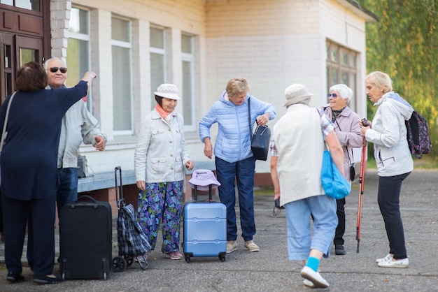 Eine Gruppe älterer Freunde mit Koffern und Taschen versammelt sich am Bahnhof, um einen Ausflug zu machen