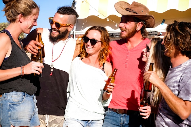 Eine Gruppe alternativer junger Kaukasier hat Spaß und genießt zusammen mit Freundschaft und Lächeln und Bierflaschen