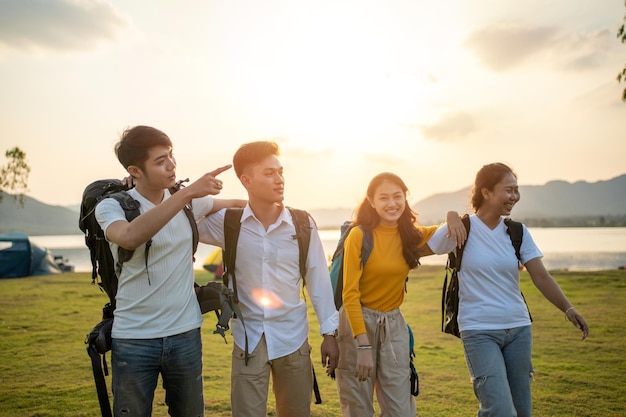 Eine Gruppe asiatischer Freunde, die mit Rucksack wandern und zum Picknick und Camping in der Nähe des Sees spazieren gehen