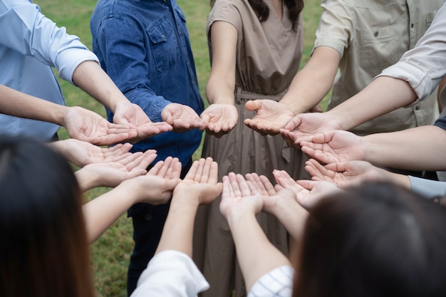 Eine Gruppe asiatischer Menschen hebt ihre rechten Hände und greift sie sanft an, um ein gutes Gefühl beim Training Teambuilding zu erhalten und zu teilen.