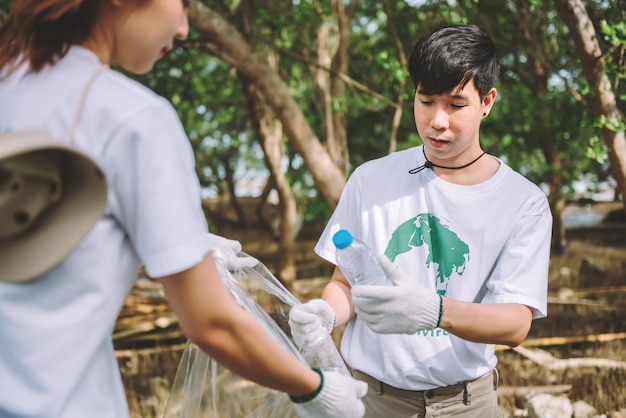 Eine Gruppe asiatischer, vielfältiger Menschen, die sich freiwillig für die Teamarbeit im Umweltschutz engagieren, helfen beim Sammeln von Plastik- und Schaummüll auf dem Parkgelände. Freiwilligenarbeit am Weltumwelttag