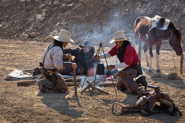 Eine Gruppe Cowboy-Männer, die sitzen, Kaffee trinken, um sich auf ihrem Campingplatz zu entspannen