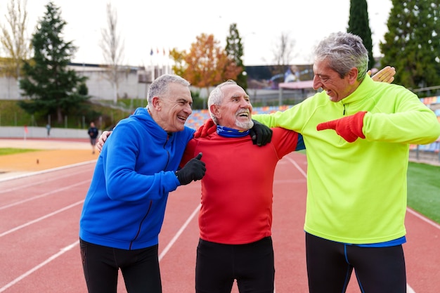 Eine Gruppe fröhlicher älterer Freunde in Sportkleidung lacht und macht nach dem Lauf freundliche Gesten