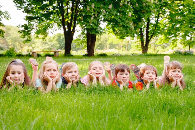 Eine Gruppe glückliche Kinder von Jungen und von Mädchen laufen in den Park auf dem Gras an einem sonnigen Sommertag