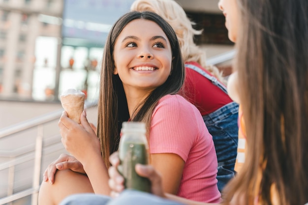 Eine Gruppe glücklicher Freunde, mehrrassige Teenager, die leckeres Eis essen und sich auf der Straße unterhalten