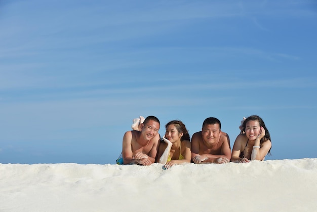 Eine Gruppe glücklicher junger Leute am schönen Sommertag am weißen Sandstrand Spaß und Freude haben