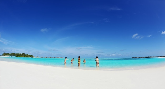 Eine Gruppe glücklicher junger Leute am schönen Sommertag am weißen Sandstrand Spaß und Freude haben