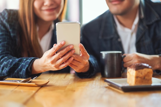 Eine Gruppe junger Asiaten, die zusammen im Café das gleiche Handy benutzen und betrachten