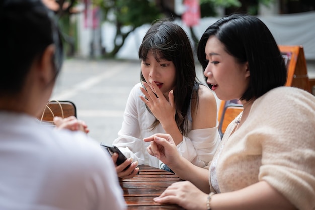 Eine Gruppe junger asiatischer Freundinnen unterhält sich gerne in einem Café in der Stadt