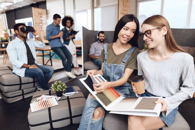 Eine Gruppe junger Designer sitzt auf gepolsterten Hockern.