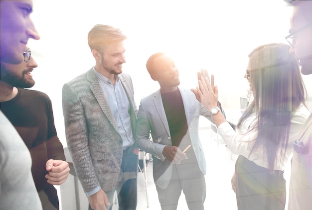 Eine Gruppe junger Kollegen, die sich gegenseitig ein High Five geben, während sie in einem Büro stehen