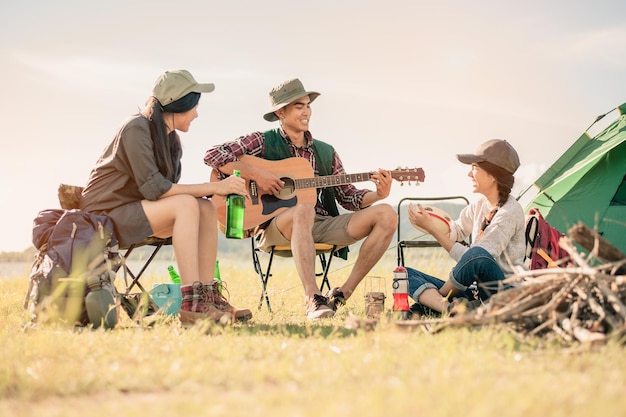 Eine Gruppe junger Leute genießt die Musik von Schlagzeug und Gitarre auf einem Campingausflug.