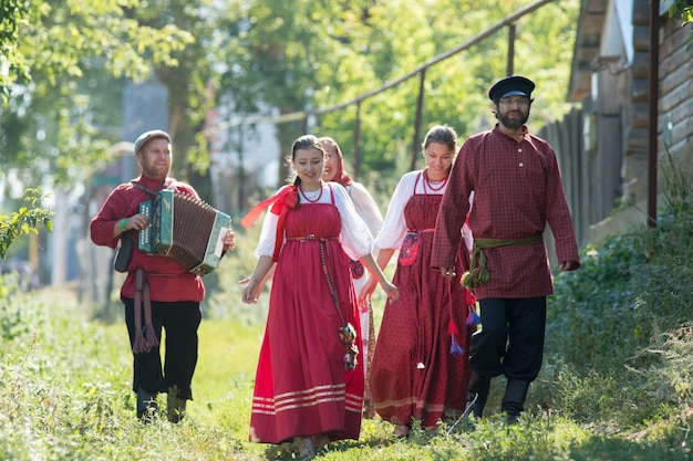 Eine Gruppe junger Leute in russischen Trachten, die durch das Dorf laufen, Nahaufnahme