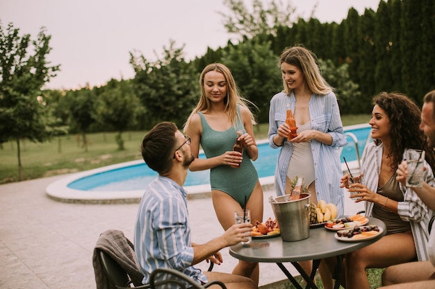 Eine Gruppe junger Leute jubelt mit Cider am Pool im Garten
