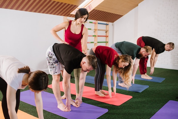 Eine gruppe junger leute macht joga-übungen drinnen im fitnessstudio