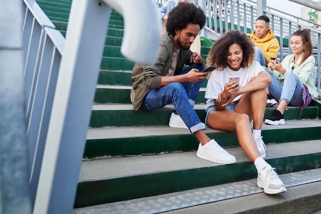Eine Gruppe junger Leute sitzt mit ihren Mobiltelefonen im Freien
