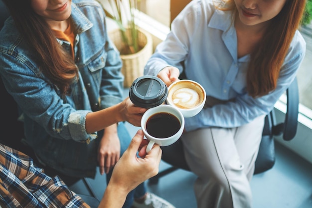 Eine Gruppe junger Leute trank und klingelte Kaffeetassen in einem Café.