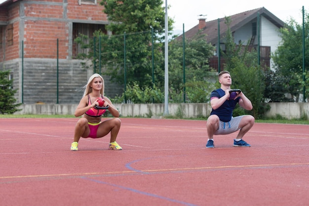 Eine Gruppe junger Menschen im Aerobic-Kurs, die im Freien eine Kettle Bell-Übung machen