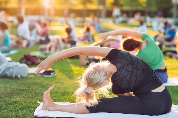 Eine Gruppe junger Menschen macht Yoga im Park bei Sonnenuntergang.