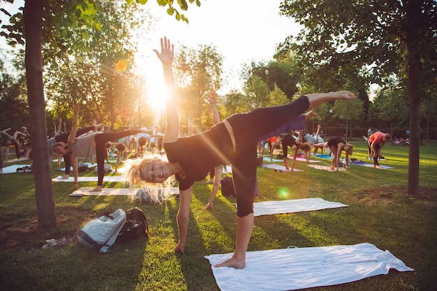 Eine Gruppe junger Menschen macht Yoga im Park bei Sonnenuntergang.