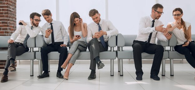 Eine Gruppe junger Mitarbeiter kommuniziert im Foto der Bürolobby mit Kopienraum