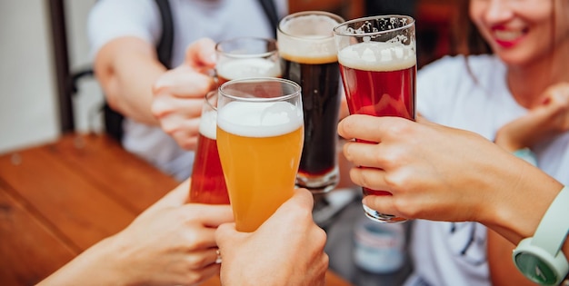 Eine Gruppe junger multiethnischer Freunde stößt auf einer Restaurantterrasse mit verschiedenen Bieren an
