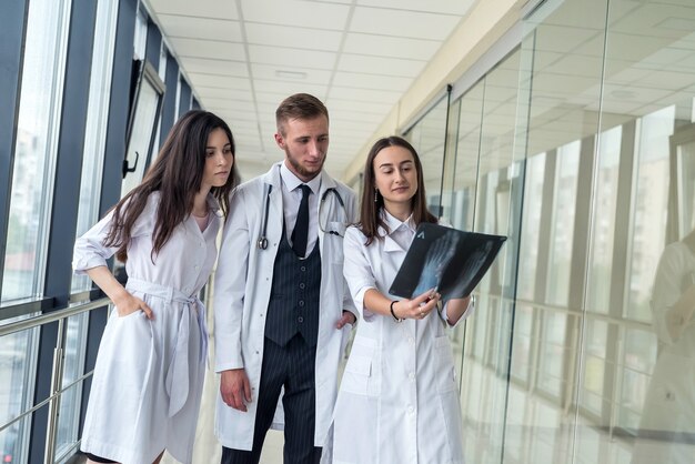 Eine Gruppe junger Ärzte bespricht und schaut in einer Klinik ein Röntgenscanbein. Konzept der medizinischen Teamarbeit