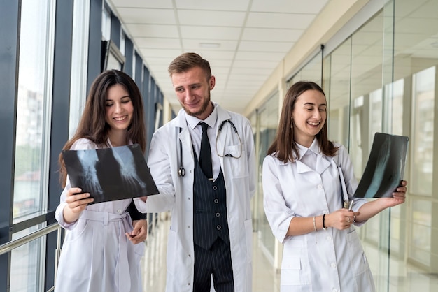 Eine Gruppe junger Ärzte bespricht und untersucht das Röntgen-Scan-Bein in einer Klinik. Konzept der medizinischen Teamarbeit