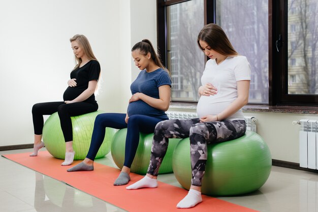 Eine Gruppe junger schwangerer Mütter betreibt in einem Fitnessclub Pilates und Ballsport. Schwanger