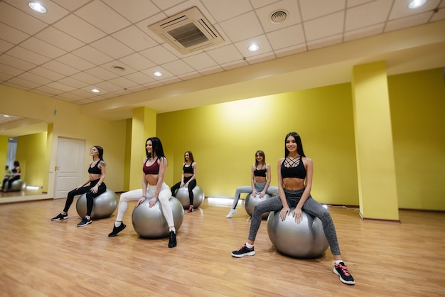 Eine Gruppe junger sportlicher Mädchen führt unter Anleitung eines Trainers Übungen im Fitnessstudio durch. Gesunder Lebensstil