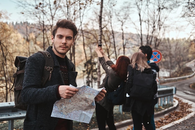 Eine Gruppe junger Touristen macht einen schönen Spaziergang im Herbstwald auf der Nebenstraße.